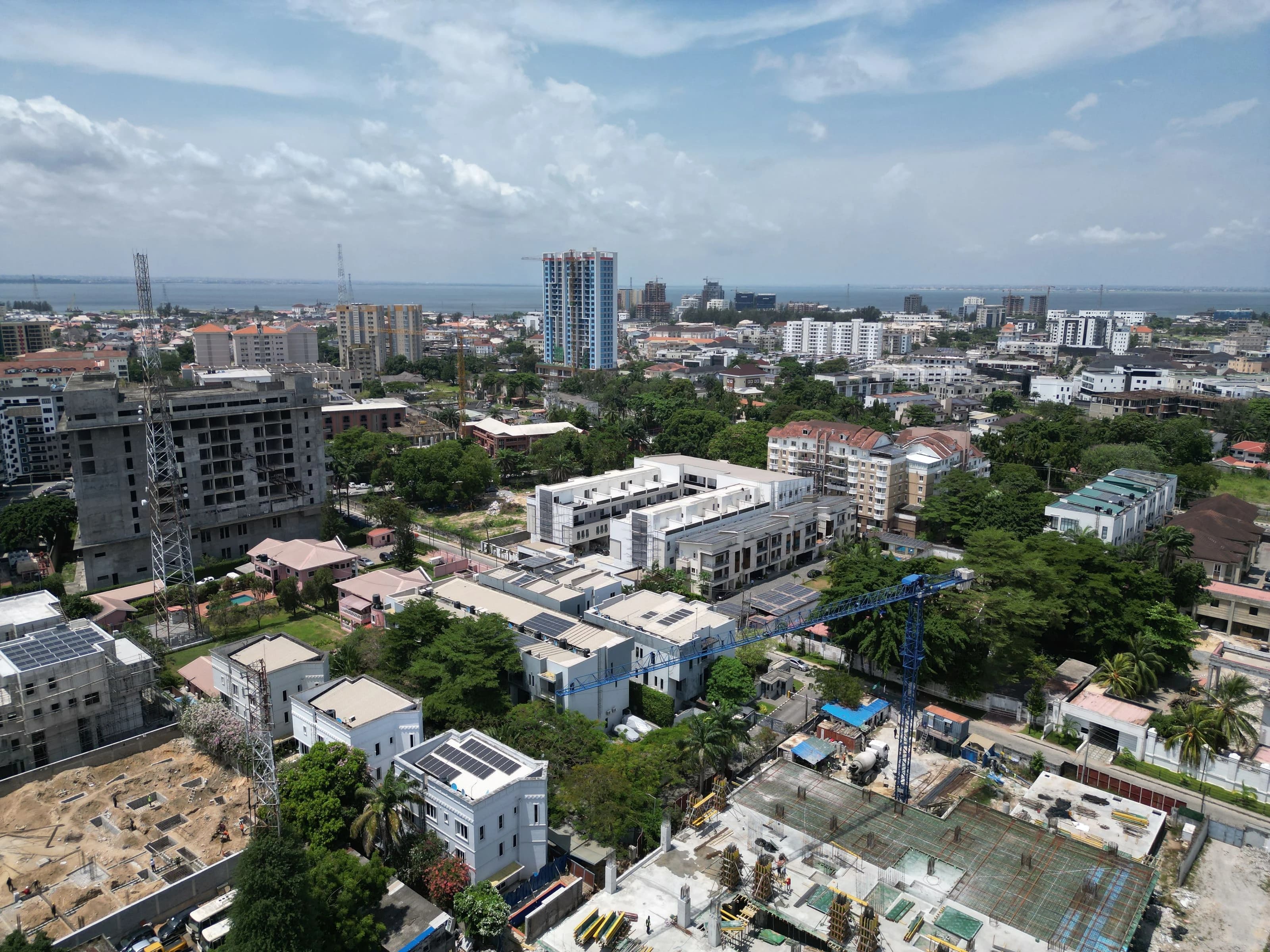 An aerial view across Lagos, Nigeria, with buildings, tree-lined streets and the ocean on the horizon.